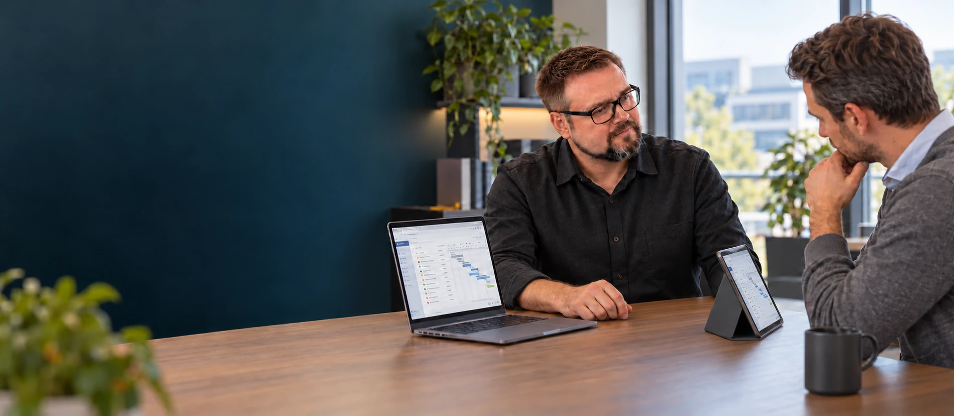 Zwei Gesprächspartner besprechen ein IT-Projekt; das iPad ist zum Kunden ausgerichtet.